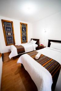 una camera d'albergo con due letti con lenzuola bianche di Tourist house 1 a Otavalo