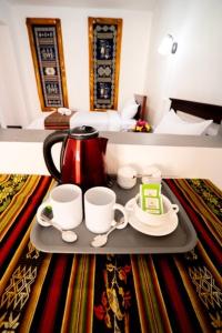 ein Tablett mit einem Wasserkocher und zwei Tassen auf einem Tisch in der Unterkunft Tourist house 1 in Otavalo