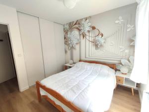 - une chambre avec un lit blanc et des fleurs sur le mur dans l'établissement Appartement avec WIFI, terrasse, jardin à TREBEURDEN Réf - 678, à Trébeurden