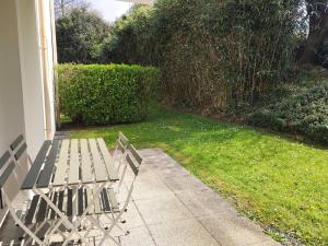 una panchina seduta su un marciapiede accanto a un cortile di Appartement avec WIFI, terrasse, jardin à TREBEURDEN Réf - 678 a Trébeurden