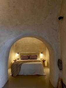 a bedroom with a bed in a stone wall at Aethra Cave Suites in Pyrgos