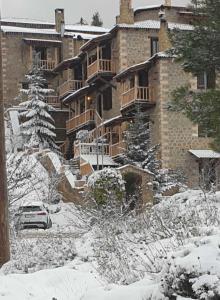 ein großes Backsteingebäude mit Schnee auf dem Boden in der Unterkunft Nymfes Guesthouse in Synikia Mesi Trikalon