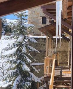 einen schneebedeckten Baum neben einem Gebäude mit Eiszapfen in der Unterkunft Nymfes Guesthouse in Synikia Mesi Trikalon