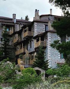 un gran edificio de piedra con balcones. en Nymfes Guesthouse, en Synikia Mesi Trikalon