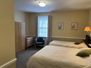 1 dormitorio con 2 camas, silla y ventana en Royal Oak Hotel, Garstang en Garstang