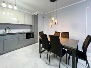 a kitchen and dining room with a table and chairs at PaVoni Terazze Verdi Łeba in Łeba