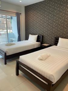 a bedroom with two beds and a wall at Norrarat Place นรรัตน์ เพลส in Chiang Rai