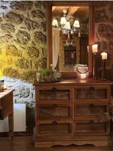 a wooden dresser with a mirror on a stone wall at Nymfes Guesthouse in Synikia Mesi Trikalon