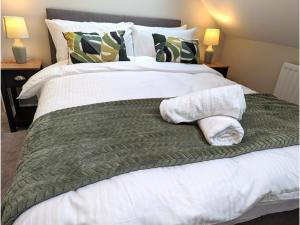 a bed with a green blanket and towels on it at 2 Bed Apt,Parking,Long Stay Offers,Reading Centre in Reading