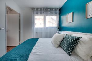 een slaapkamer met een wit bed en een blauwe muur bij Appartement cosy et calme in Élancourt