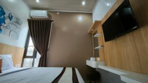 a bedroom with a bed and a flat screen tv at Premier Homestay Syariah in Kalasan
