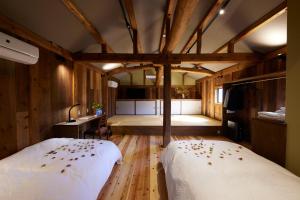 2 Betten in einem Zimmer mit Holzwänden und Holzböden in der Unterkunft ゲストハウス長閑 in Toyooka