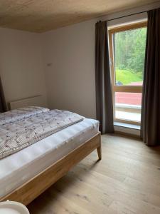 een slaapkamer met een bed en een groot raam bij Appartements Luxner in Achenkirch