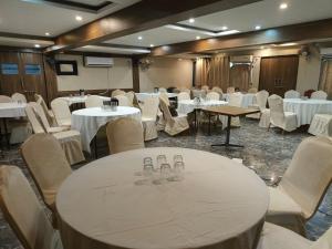 un salón de banquetes con mesas y sillas blancas en Hotel Tulsi, en Vadodara