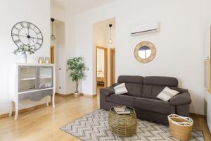a living room with a couch and a clock on the wall at Malagaflat City Center in Málaga