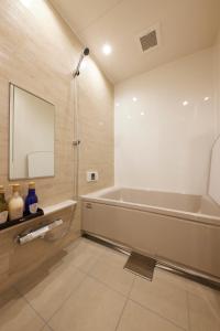 uma casa de banho com uma banheira e um espelho. em ゲストハウス長閑 em Toyooka