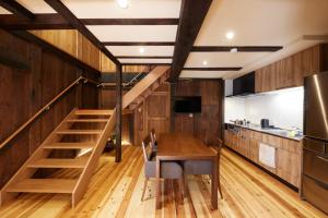 cocina y comedor con mesa de madera y escaleras en ゲストハウス長閑, en Toyooka