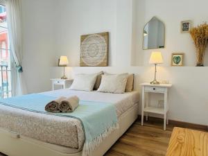 1 Schlafzimmer mit einem Bett, 2 Tischen und einem Spiegel in der Unterkunft Bright & Breezy MERCED in Málaga