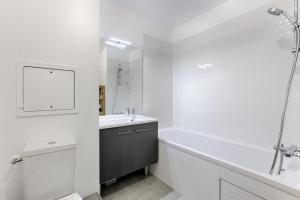 uma casa de banho branca com uma banheira e um lavatório em Résidor - Sublime Bright Apartment em Asnières-sur-Seine