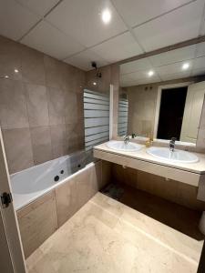 ein Badezimmer mit zwei Waschbecken und einer Badewanne und einem Spiegel in der Unterkunft Beautiful apartment,3 min drive from the beach in Bahia de Casares