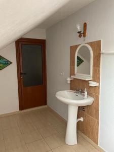 a bathroom with a sink and a mirror and a door at Eiffel's Guest House in Pogradec