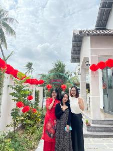 trzy kobiety stojące przed budynkiem z różami w obiekcie Bốn Mùa homestay w mieście Phu Yen