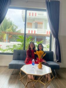 dwie kobiety siedzące na kanapie ze stołem w obiekcie Bốn Mùa homestay w mieście Phu Yen