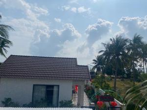 ein weißes Haus mit Palmen im Hintergrund in der Unterkunft Bốn Mùa homestay in Phu Yen