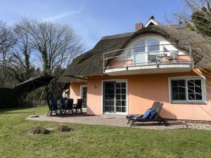 a house with a thatch roof with chairs and an umbrella at Ferienhaus Fiete in Wieck in Wieck