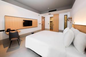 a bedroom with a bed and a desk and a television at Ando Hotel Batam in Nagoya