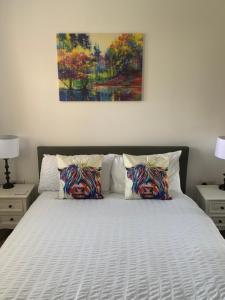 a bed with two pillows and a painting on the wall at New Holliday Villa, Anstruther in Cellardyke