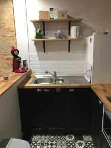 La cuisine est équipée d'un évier et d'un réfrigérateur blanc. dans l'établissement Maison Traditionnelle Périgourdine, à Hautefort