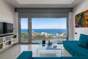 a living room with a blue couch and a large window at RhodesRentalsgr presents Rhodes Skyline Suites in Ixia