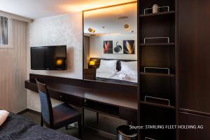 a hotel room with a desk and a bed and a mirror at KD Moment Premium Hotelship Köln in Cologne