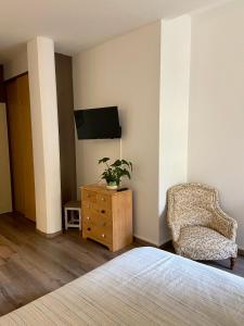 ein Schlafzimmer mit einem Bett, einem Stuhl und einem TV in der Unterkunft Casa-Belle Chambres d hotes in Sérignan