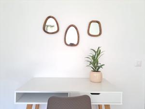 einen weißen Schreibtisch mit Topfpflanze und 3 Spiegeln in der Unterkunft Airolo Valley Apartments by Quokka 360 - Cozy with Mountain View in Airolo