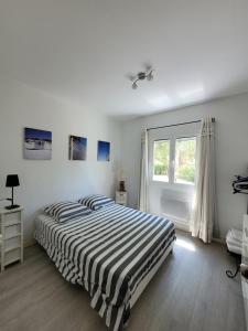 a white bedroom with a bed and a window at Maison pieds dans l eau St Florent in Saint-Florent