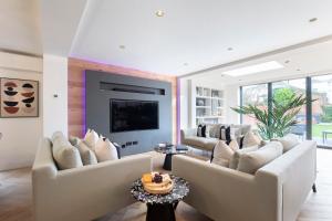 uma sala de estar com sofás brancos e uma televisão em Elliot Oliver - Superior 6 Bedroom House in Cheltenham With Hot Tub & Log Burner em Cheltenham