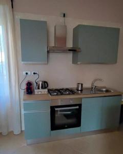 La cuisine est équipée de placards bleus et d'un four avec plaques de cuisson. dans l'établissement Il Sole Dentro Holiday Home, à Pellezzano