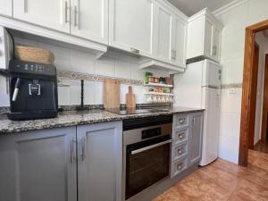 オリウエラにあるFamilienhaus in Cabo Roigの白いキャビネットとコンロ付きオーブンを備えたキッチン