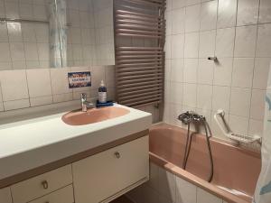 W łazience znajduje się umywalka i różowa wanna. w obiekcie Les Rossets w mieście Boudry
