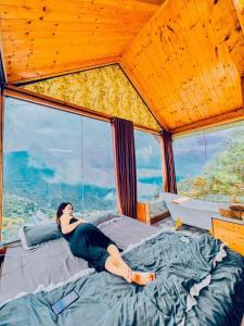 een vrouw op een bed in een kamer met een raam bij mimosa villa tam dao in Tam Ðảo