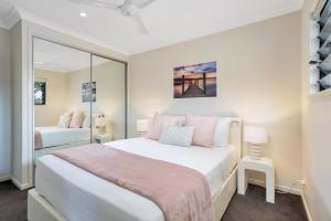 a bedroom with a large bed with pink pillows at Nature View Southside Apartment in Cairns