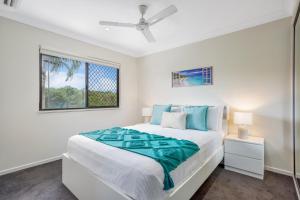 a white bedroom with a bed and a window at Nature View Southside Apartment in Cairns