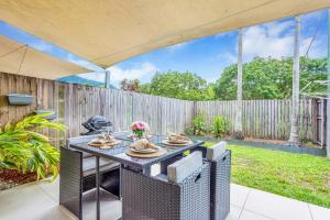 a patio with a table and chairs and a fence at Nature View Southside Apartment in Cairns