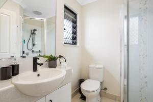 a white bathroom with a sink and a toilet at Nature View Southside Apartment in Cairns