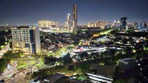 eine nachts beleuchtete Stadt mit Gebäuden in der Unterkunft Studio Apartment JiExpo Kemayoran Sunrise View -Min Stay 3 nights- in Jakarta