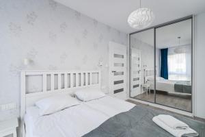 グディニャにあるLTC Apartments Ujejskiegoの白いベッドルーム(ベッド1台、大きな鏡付)