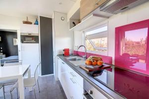 uma cozinha com um balcão com um lavatório e uma janela em Cottage Premium, camping 5* avec parc aquatique em Hudimesnil