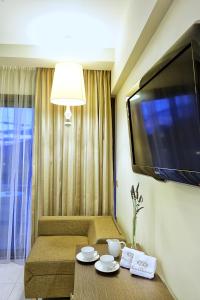 uma sala de estar com um sofá e uma televisão de ecrã plano em Sivota Diamond Spa Resort em Sivota